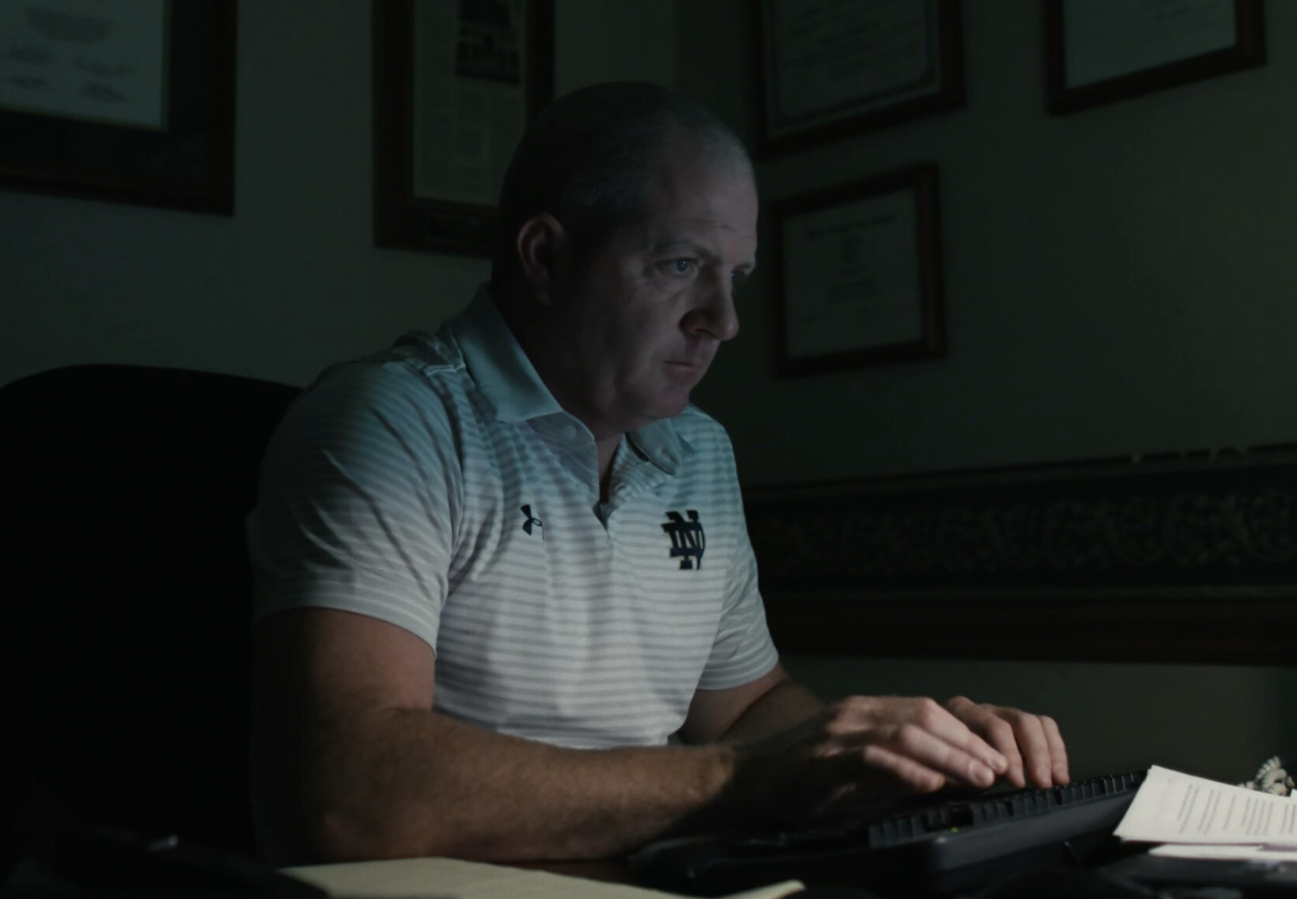 Attorney Paul Farrell Jr. sitting in a dark room and typing on a keyboard.